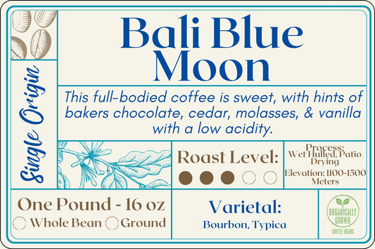 A modern and elegant coffee bag label for Bali Blue Moon Coffee. The label features a combination of blue and brown hues, reflecting sophistication. Text on the label describes the coffee's origin, roast level, varietal, growth elevation, processing method, and organic cultivation
